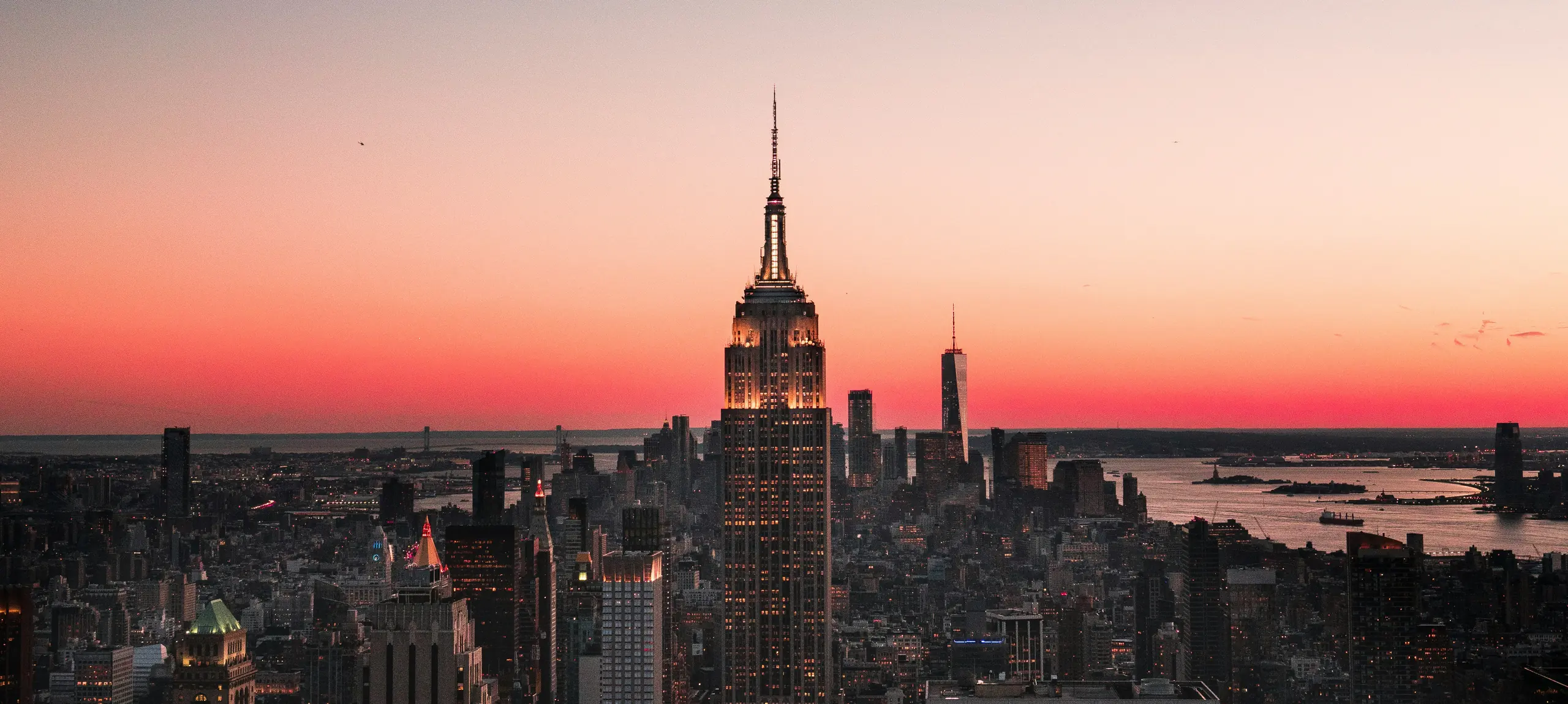 Manhattan at dusk, the Empire State Building lit against a red sunset